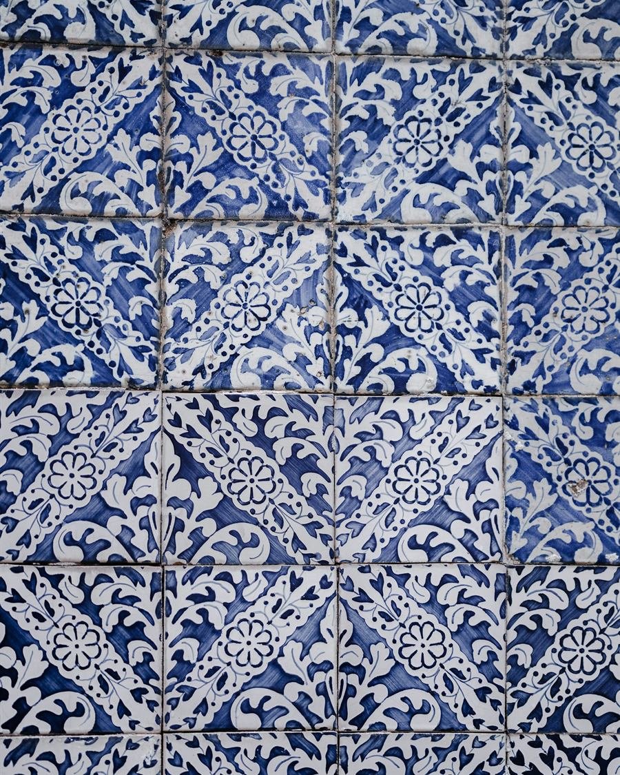Fachada de casa tradicional revestida a azulejos portugueses verdes, com porta de madeira