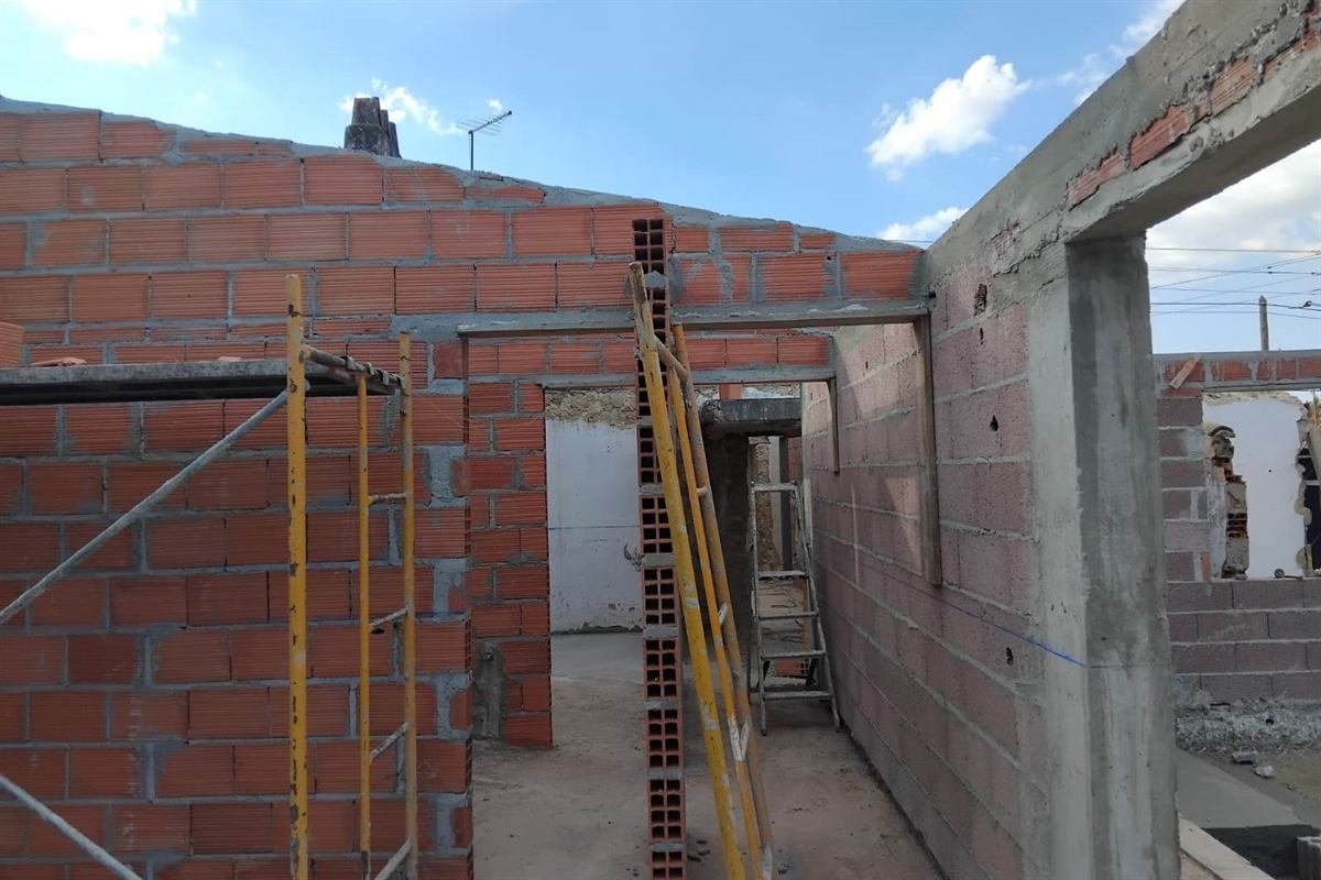 Paredes de alvenaria de uma moradia em obra, com andaime e céu limpo