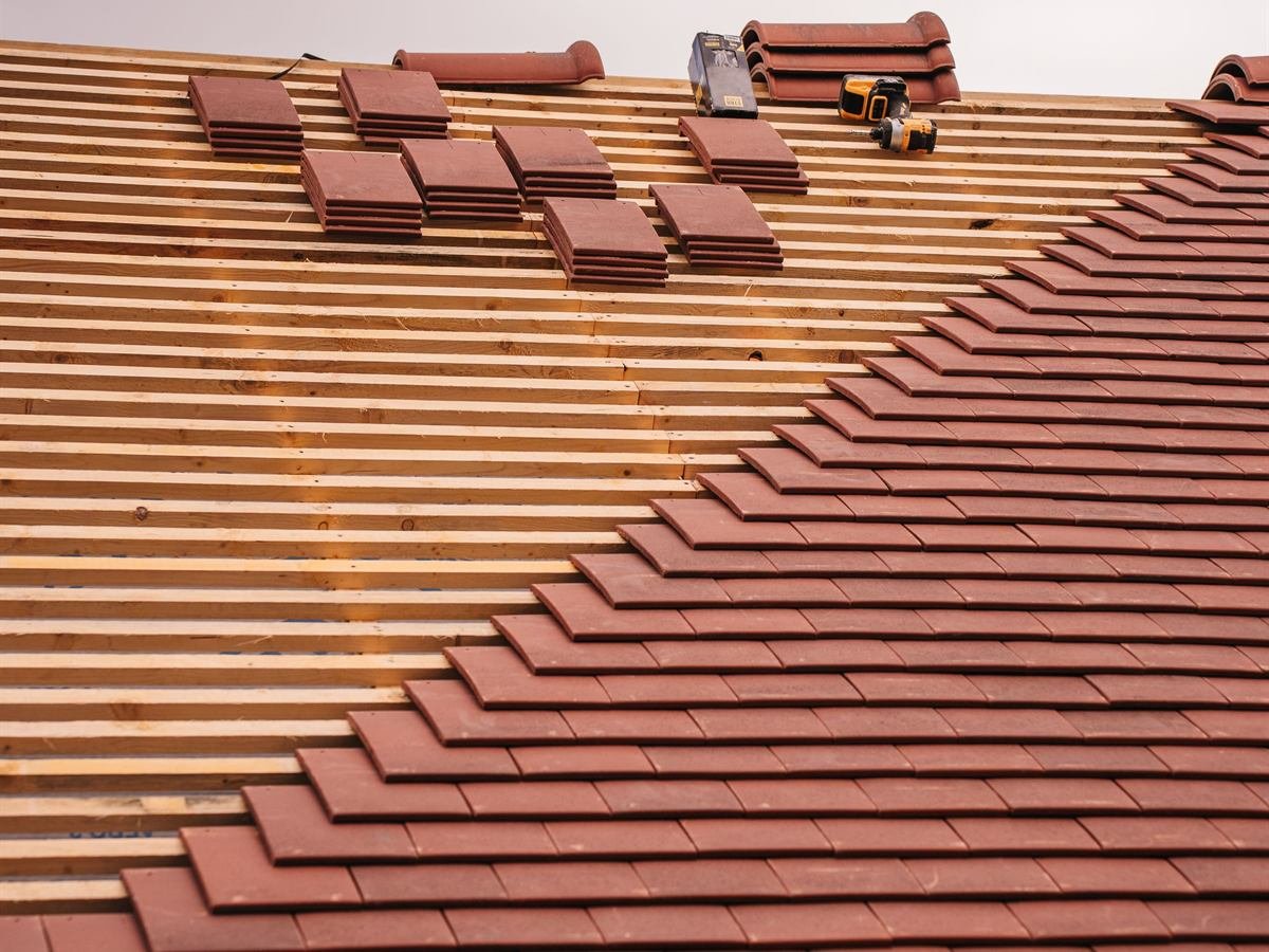 Colocação de telha cerâmica de barro numa cobertura em construção